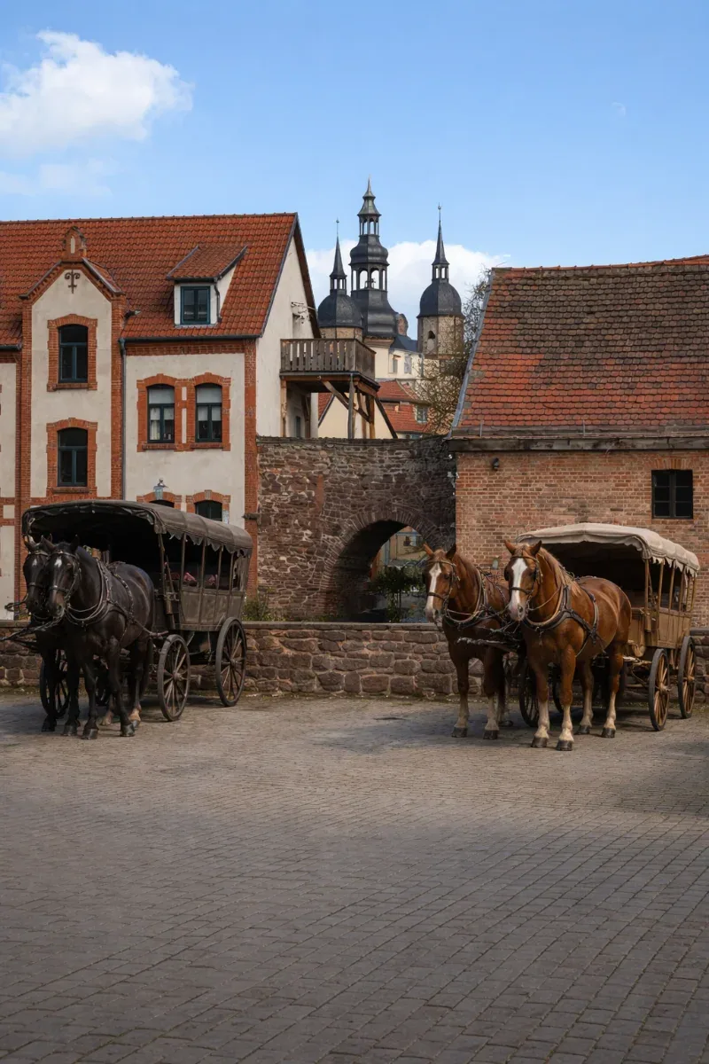 Historische Darstellung der Bäckergasse in Eisleben mit Pferdekutschen statt Autos und Blick auf die St.-Andreas-Kirche