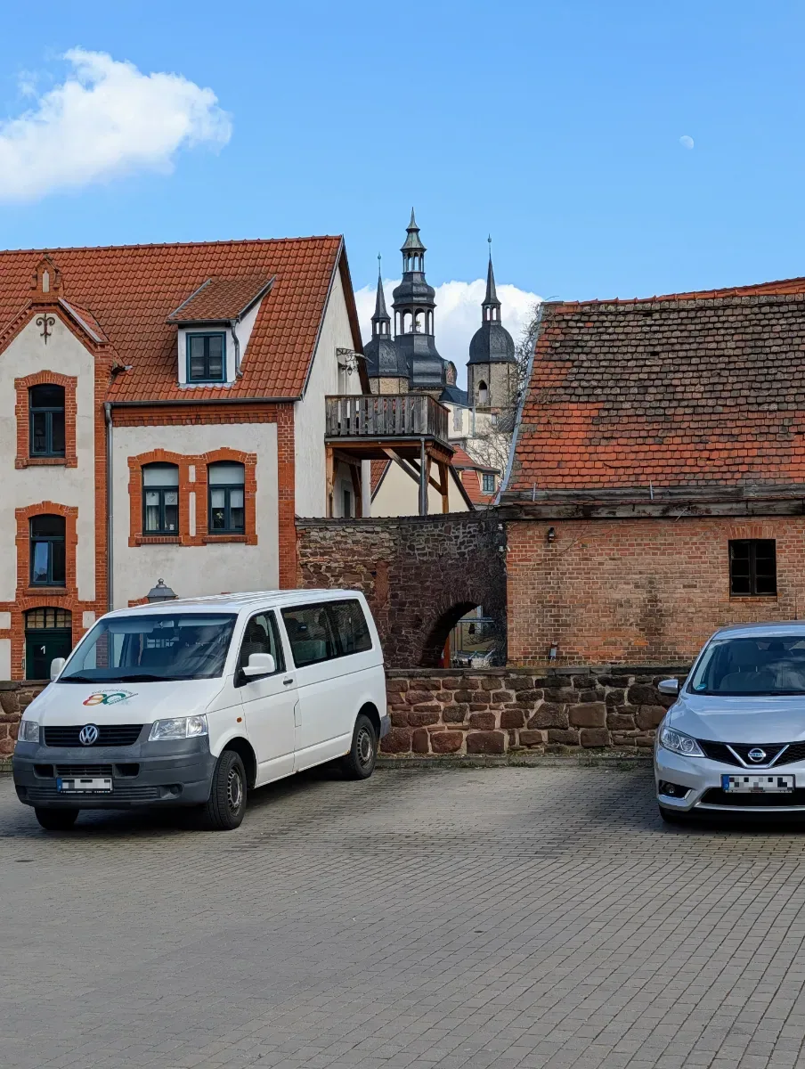 Parkplatz Bäckergasse in Eisleben mit Blick auf die Altstadt und St.-Andreas-Kirche, moderne Autos im Vordergrund
