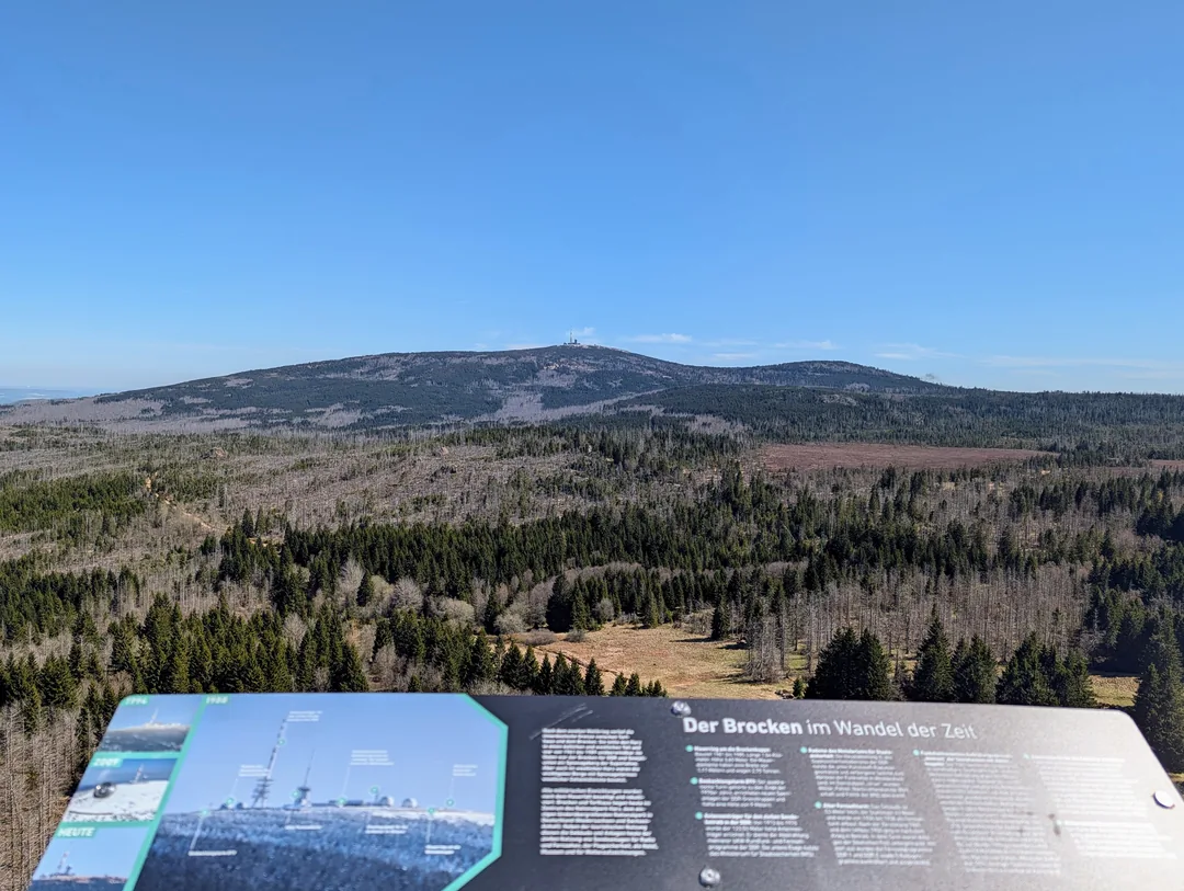Infotafel zum Brocken auf dem Skywalk des Harzturms, im Hintergrund der Brockenfelsen