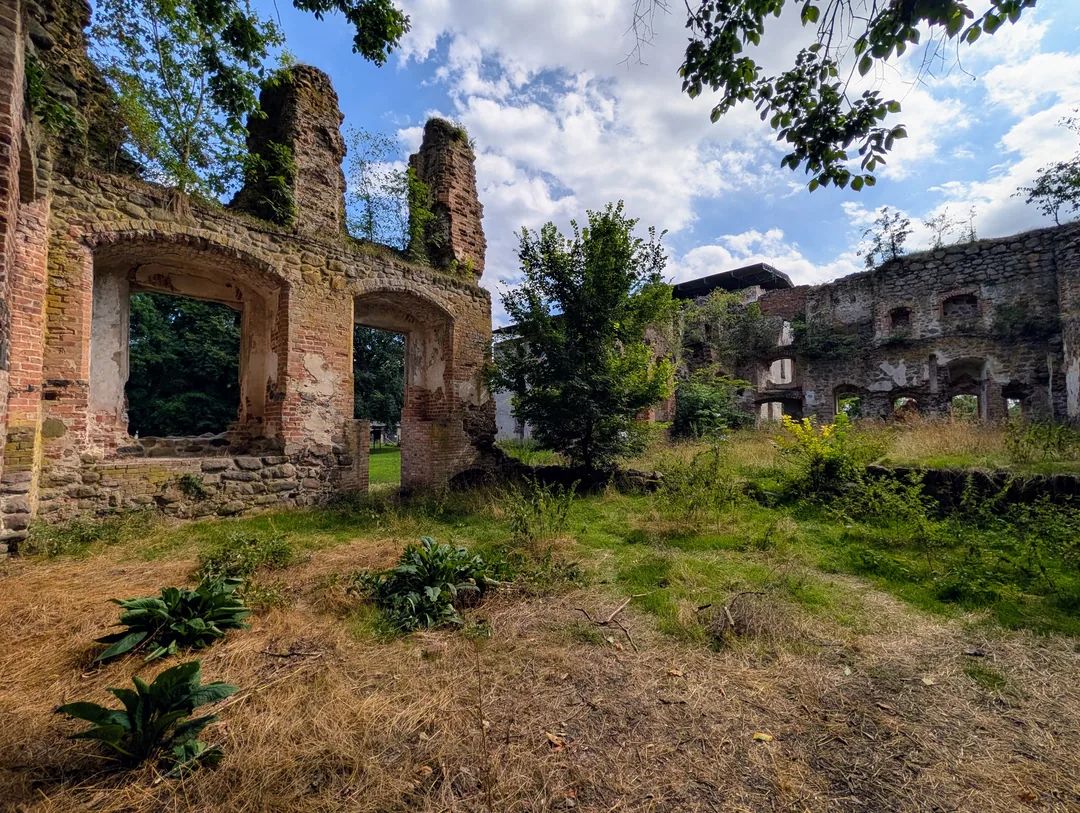 Zwei große Bogenöffnungen im Inneren der Schlossruine Putzar mit Blick in den Park