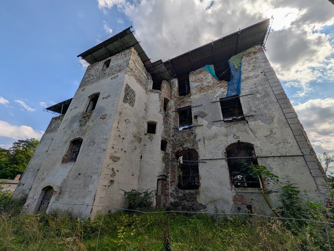 Der Ulrichsbau in Putzar von unten fotografiert, mit Wellblech-Notdach auf Stahlgerüst