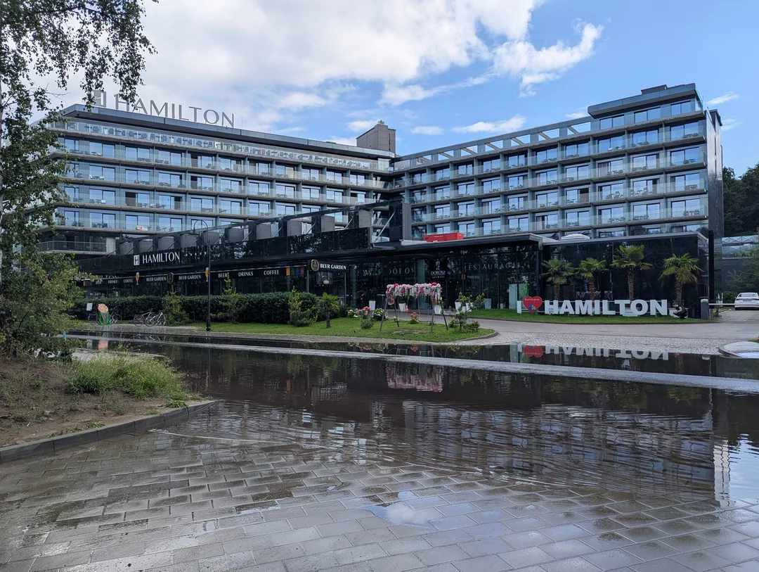 Hotelfassade in Świnoujście, gespiegelt in einer Regenpfütze auf der Promenade
